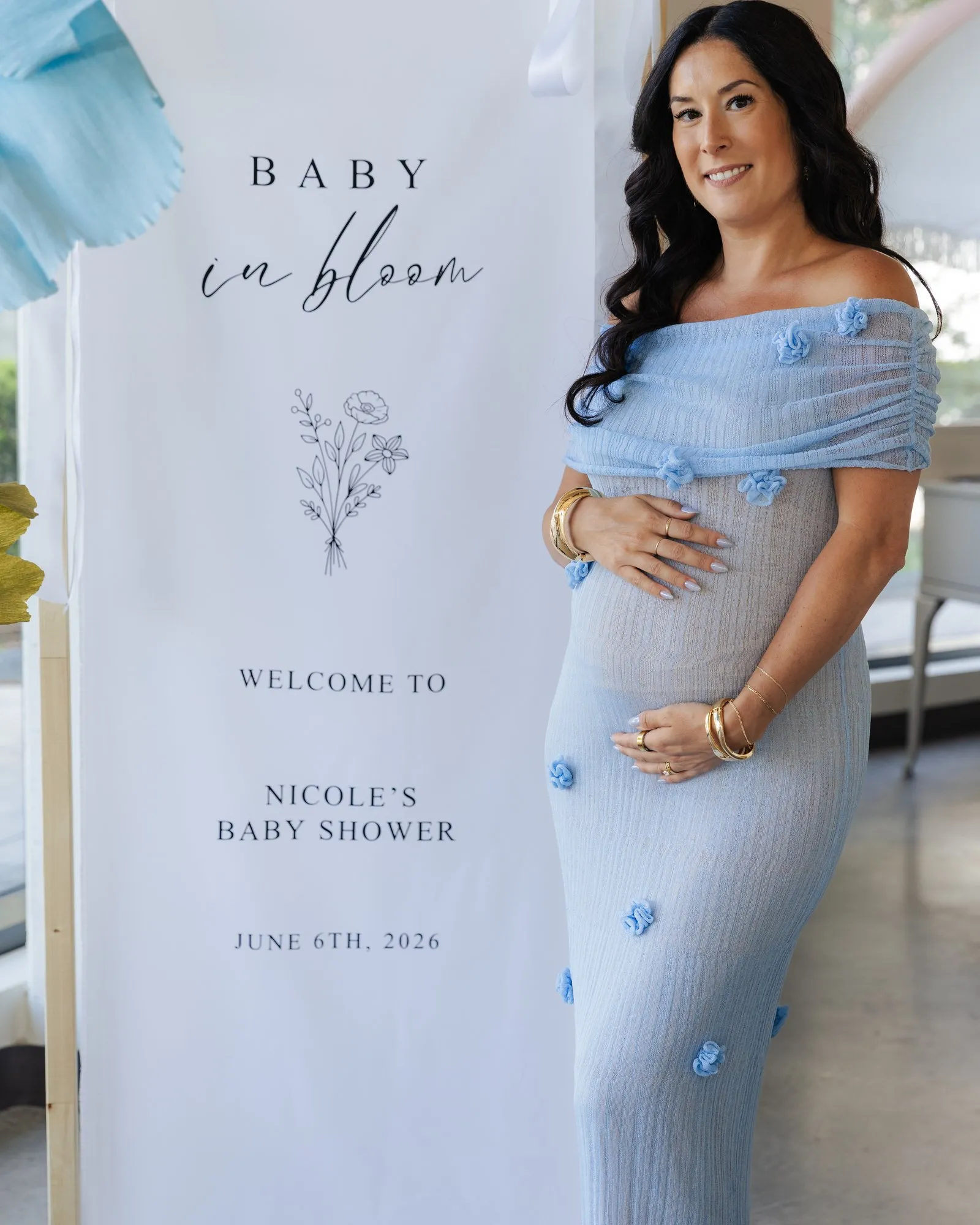 Nicole beside the floral "Baby in bloom" welcome sign