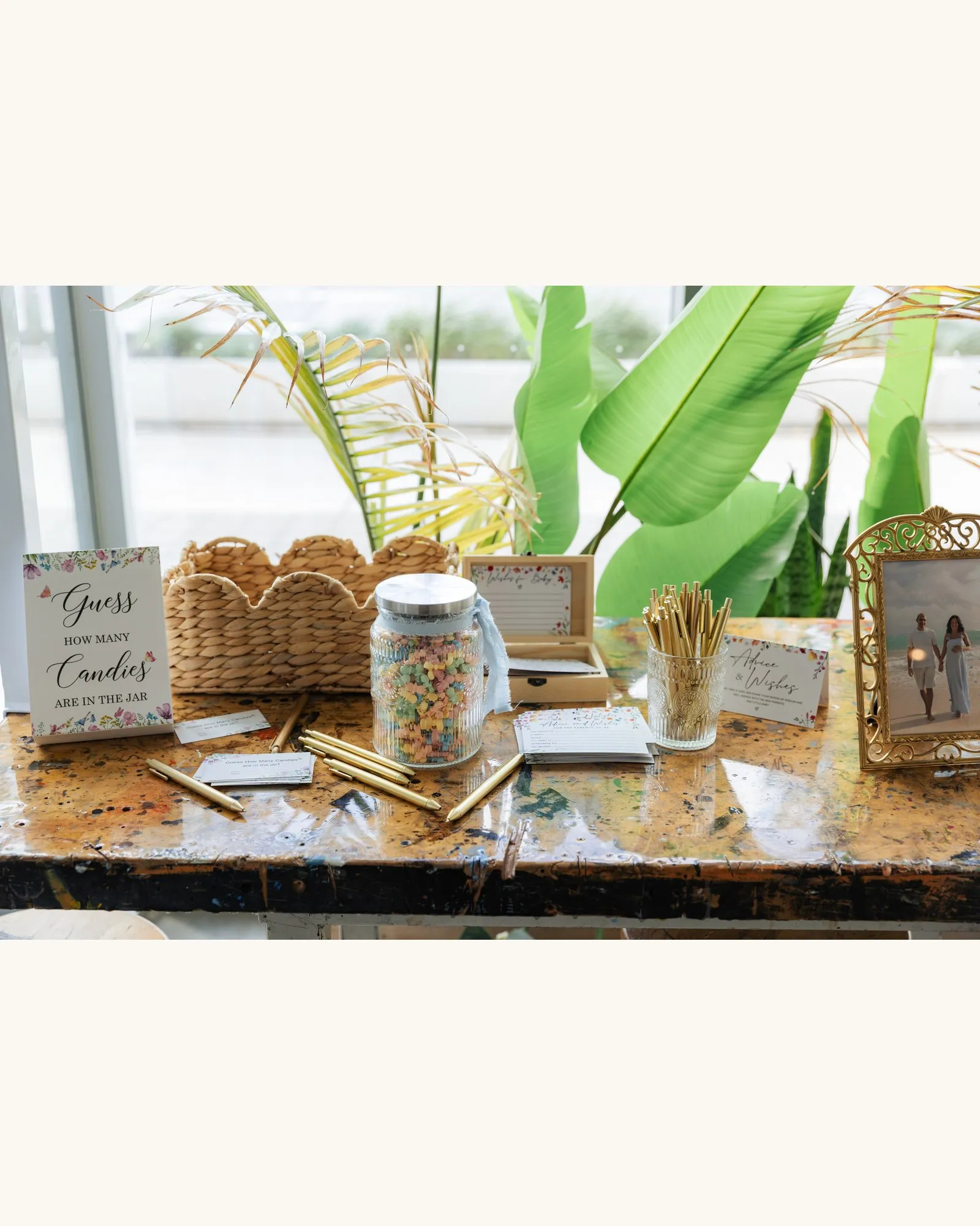 Games table with a "Guess how many candies" jar, gold pens and an advice and wishes card