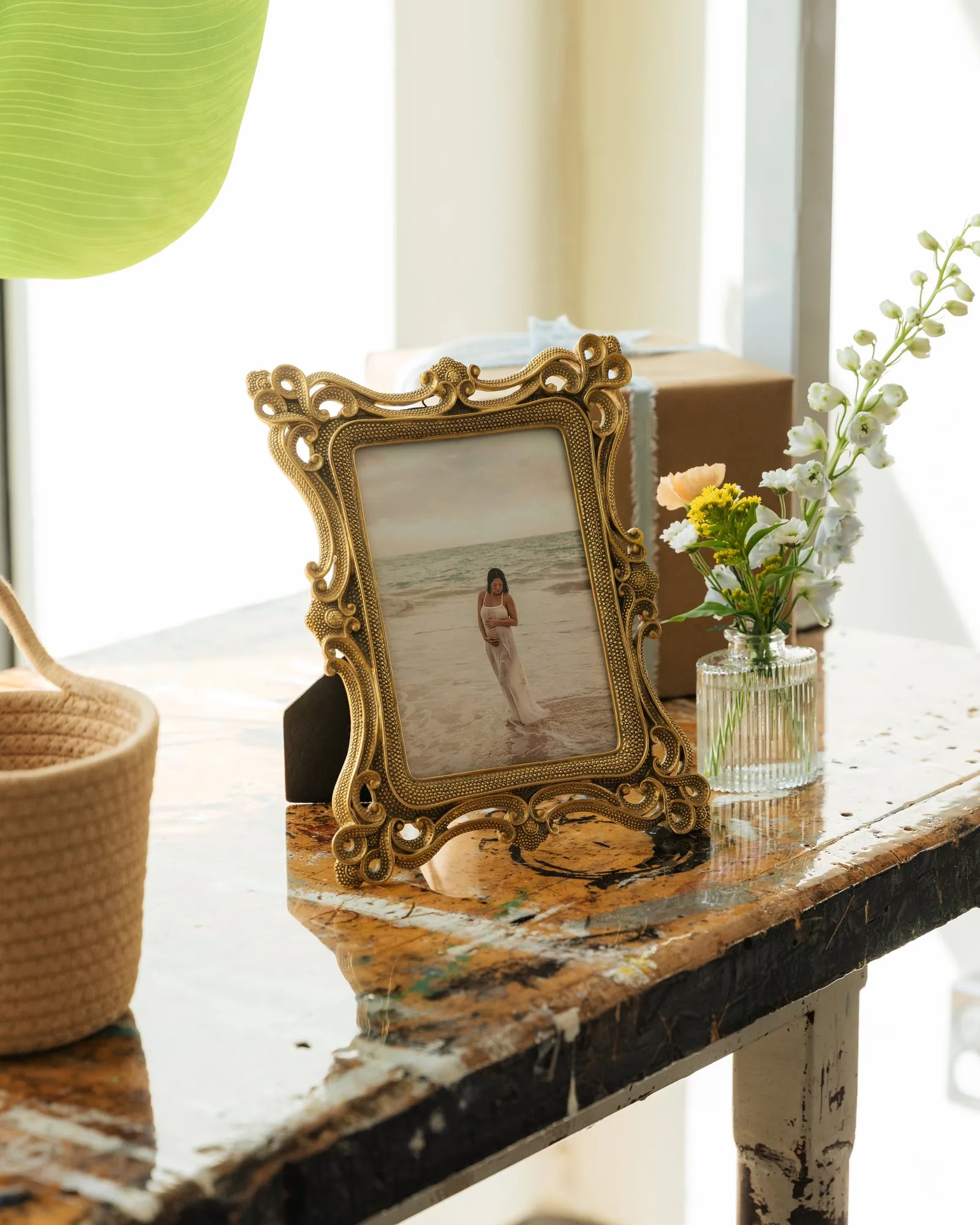 Gold-framed maternity photo beside a bud vase of delphinium and wildflowers